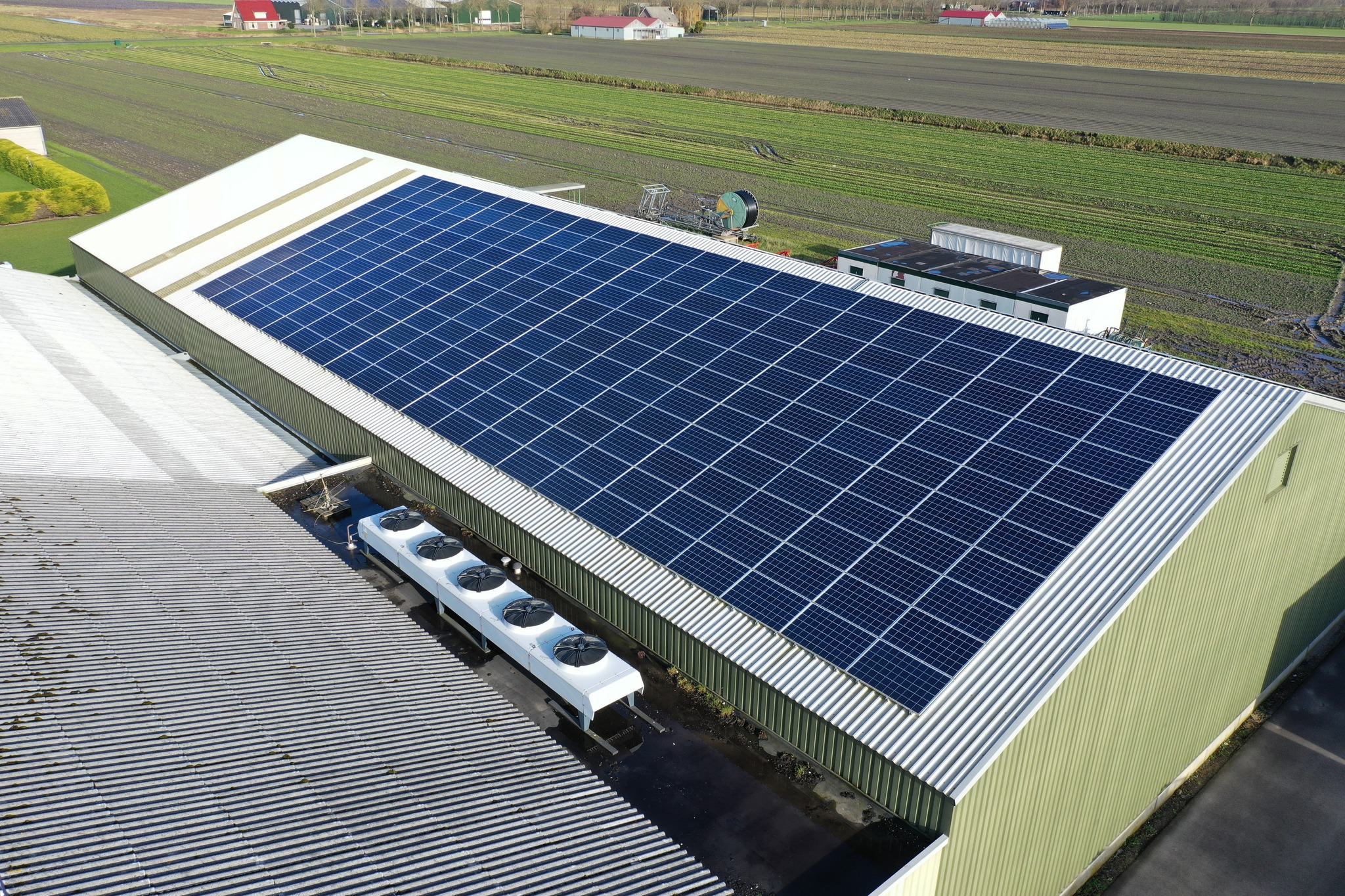 Solar panels on a roof of a company colored blue by sunlight. Solar panels are a cheap and sustainable way to get energy from sunlight. Photo taken with a flying drone